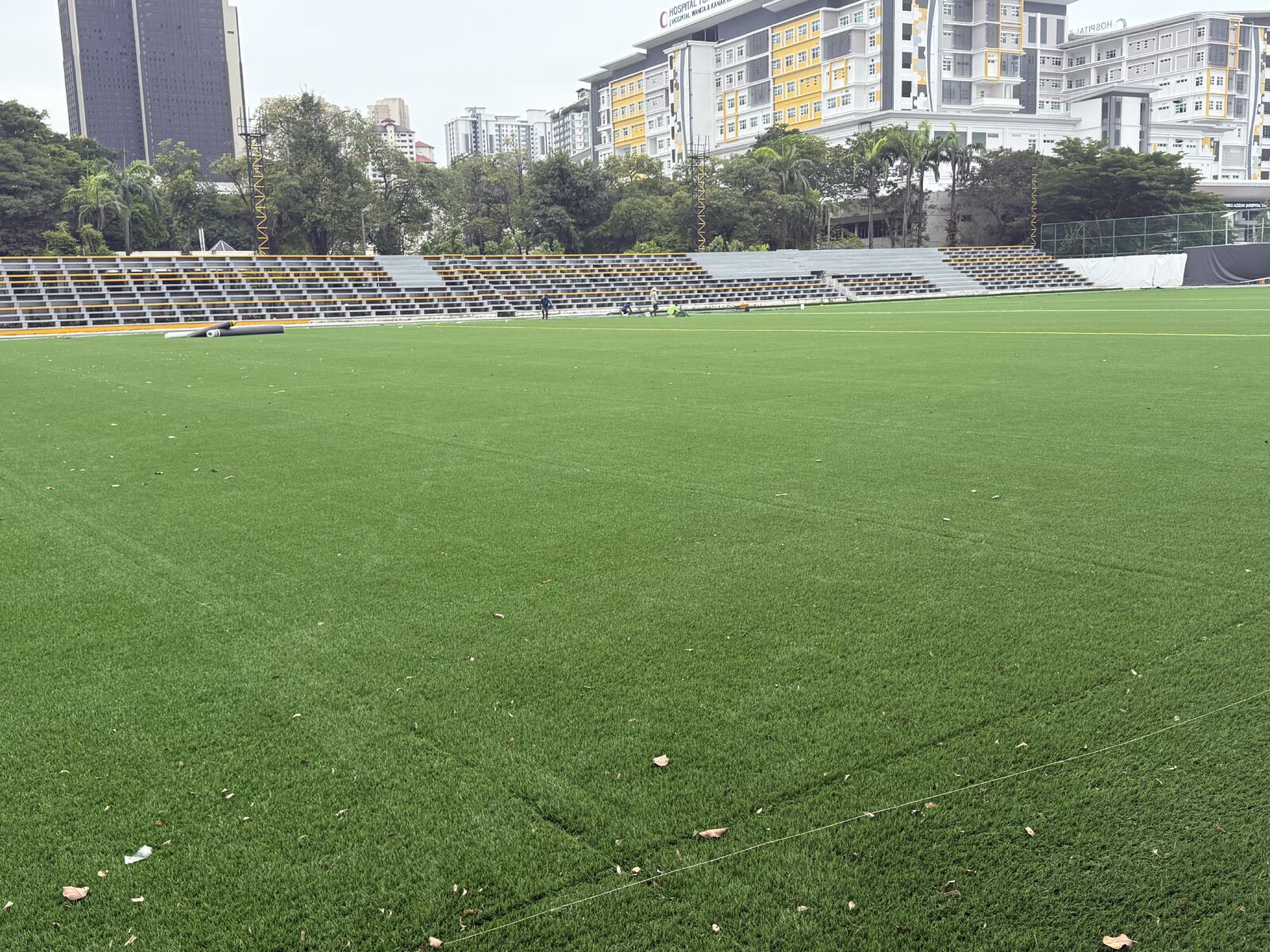 Daytime view of the SJM1 Arena turf with spectator stands and city buildings